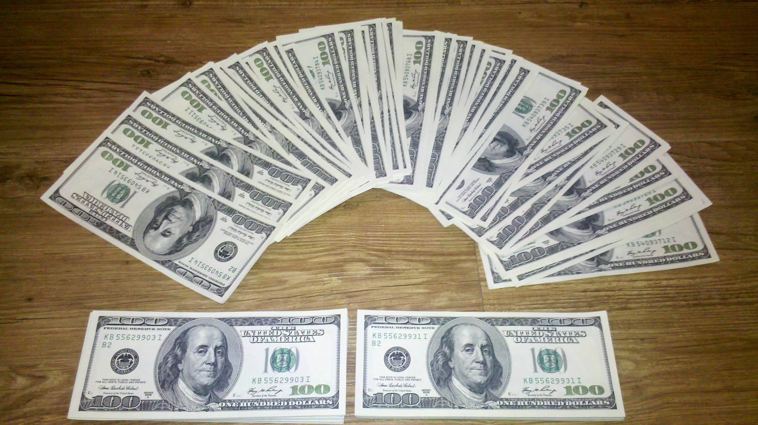 US hundred-dollar banknotes spread in a fan on a wooden surface