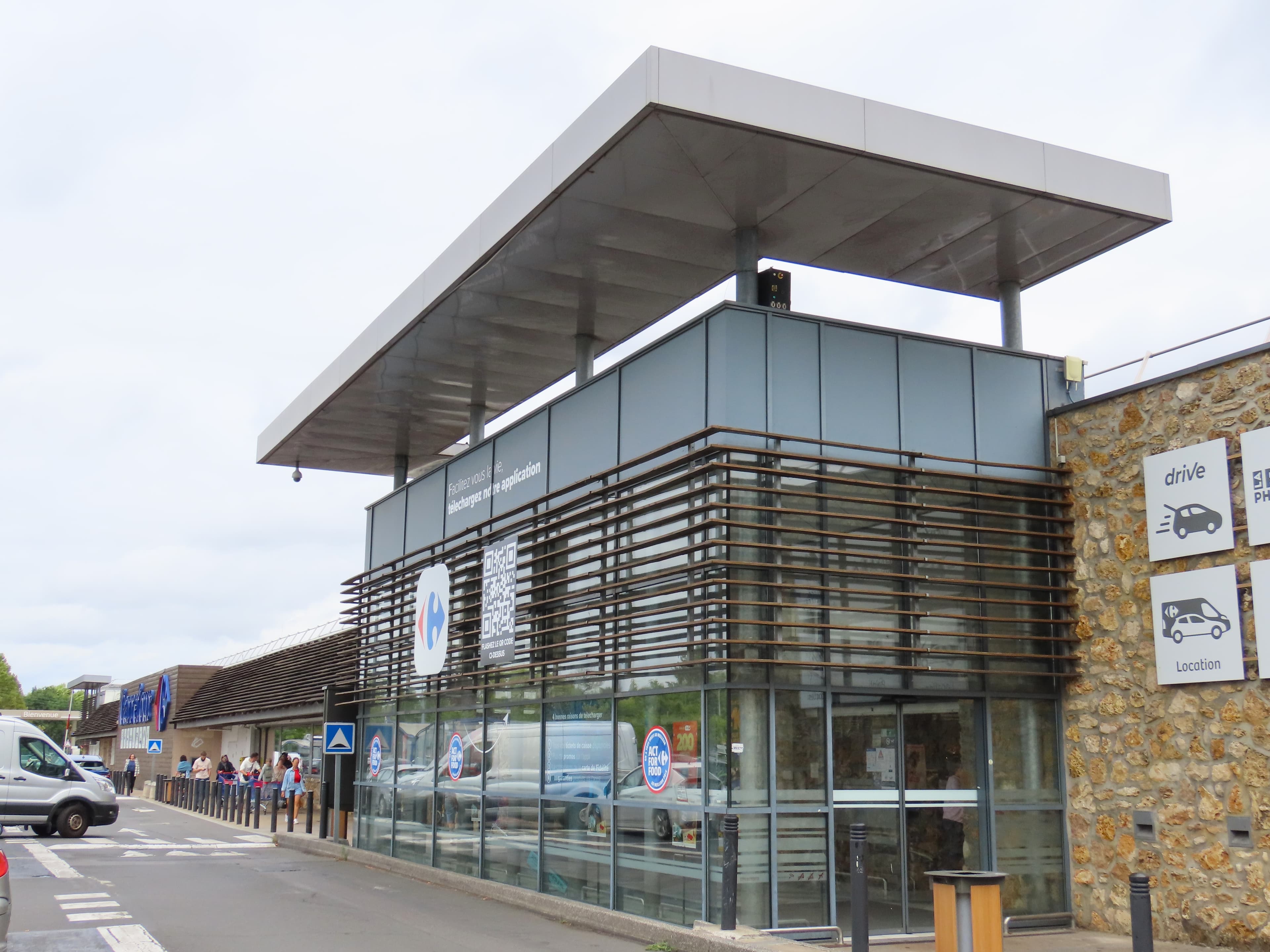 The entrance and signage of a Carrefour supermarket in Sainte-Geneviève-des-Bois, France.