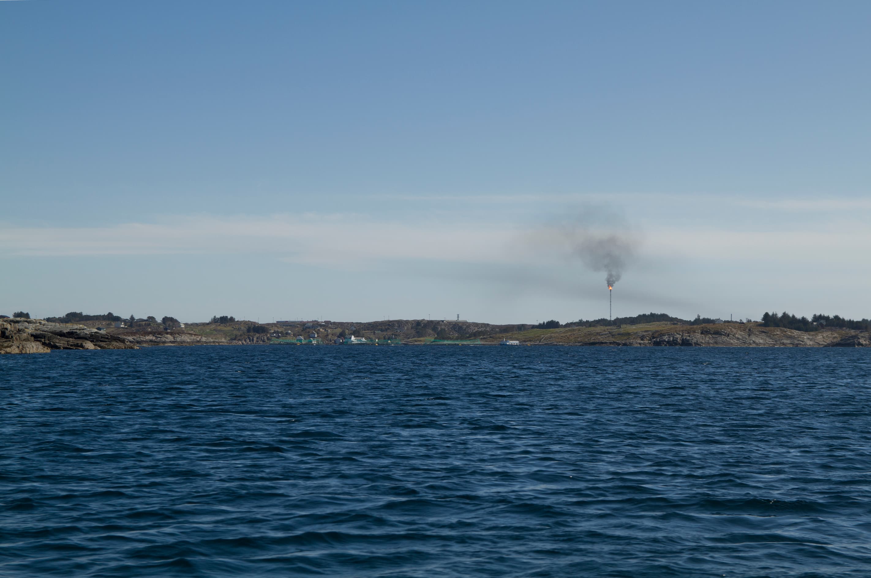 A gas flare on the shoreline at Kollsnes in Norway, seen across the water.