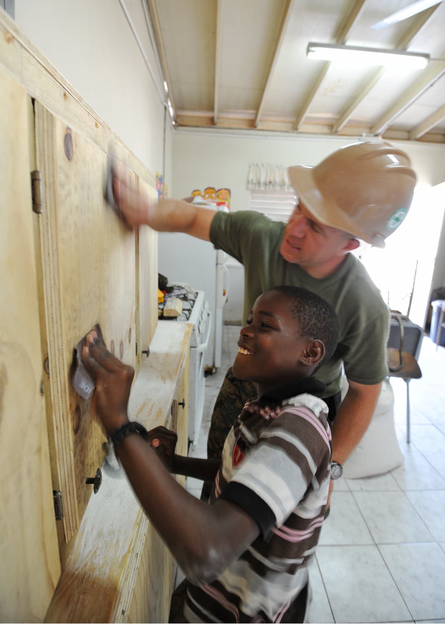 A worker and child sand a wooden cabinet at Trenchtown Primary School in Kingston